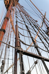 Obraz premium Tall Ship Mast with Furled Sails and Rigging Against Clear Sky
