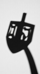 Dramatic monochrome shadow of a Hanukkah dreidel, evoking holiday tradition and spiritual
