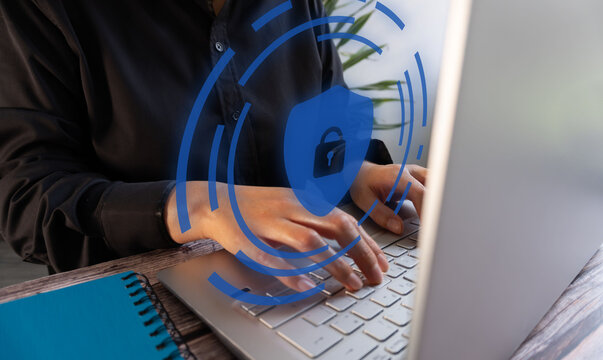 Cybersecurity concept. Woman working on a computer with a shield icon with a padlock.