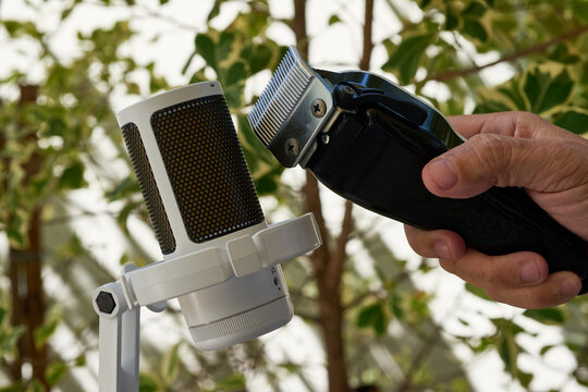 ASMR haircut sound. Hands holding electric hair clippers near microphone.