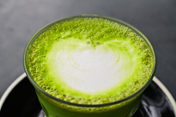 Extreme close up view of hot matcha latte with black or grey table. gray. Landscape. cafe, coffee shop. texture, detail, surface.
