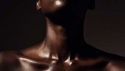Close-up of highly oiled dark skin on the neck and clavicles under dramatic studio lighting.