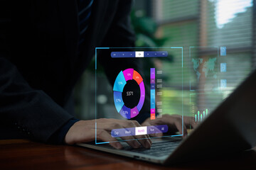 A business professional analyzing a holographic data dashboard on a laptop, showcasing digital analytics, performance metrics, and futuristic technology used for insight-driven decision-making.