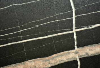 Black marble with large parallel veins, close-up of the polished surface of the natural stone.