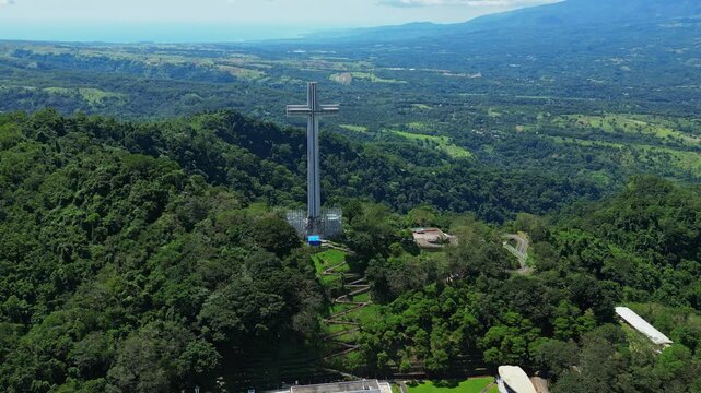 Overhead dolly zoom aerial emphasizing the towering Mt. Samat National Shrine, framed by lush forested hills and expansive mountain views in Pilar, Bataan, Philippines.