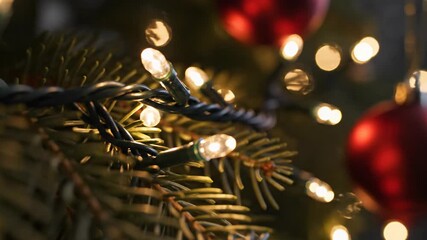 Close-up of Christmas tree with sparkling lights and red ornaments festive holiday season.