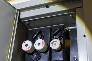 A close-up view reveals the interior components of a main electrical fuse box, showing two black...