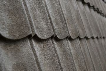 A detailed, high-angle close-up of dark grey, corrugated metal roof tiles, showing a repeating pattern of wavy curves and subtle texture. Perfect for 3d rendering.