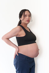 Pregnant woman with bare belly and hands on her hips.