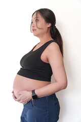 Full body side portrait of a beautiful pregnant woman holding her belly isolated on a white background.