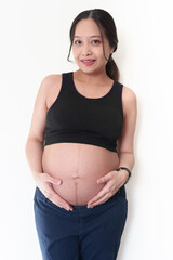 Front view of happy pregnant woman smiling and touching belly.