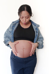 Beautiful young pregnant woman in good fit holds hands on her belly. Happy mother waiting for baby birth during pregnancy.