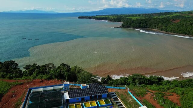 Pull‑out aerial of Nagbayog View Deck in Mariveles, Bataan, showing striking contrast between blue and brown coastal waters as the drone rises above the nearby power plant.