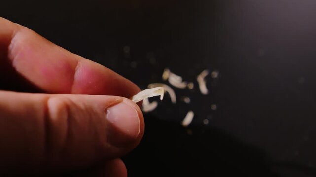 Detailed view of fingernails gripping sharp-edged toenail on black surface