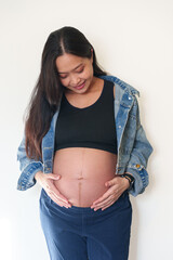 Beautiful young pregnant woman in good fit holds hands on her belly. Happy mother waiting for baby birth during pregnancy.