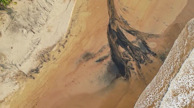 Top‑view spinning aerial highlighting the striking black sand patterns along the shoreline, with waves rolling in and lush tropical scenery at Quinawan Beach in Mariveles, Bataan, Philippines.