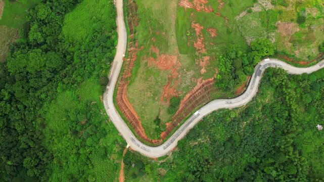 Slow rotating downward aerial of Quinawan Mountain View in Mariveles, Bataan, revealing winding roads, dense green trees, and rolling hills leading toward the coast.