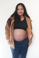 Beautiful young pregnant woman in good fit holds hands on her belly. Happy mother waiting for baby birth during pregnancy.