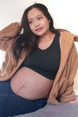 Beautiful young pregnant woman in good fit holds hands on her belly. Happy mother waiting for baby birth during pregnancy.