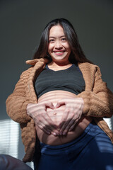Pregnant Woman Making Heart Shape on Stomach: Prenatal Care, Pregnancy Wellness, and Maternity Health