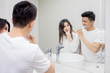 Attractive young Asian couple maintaining dental hygiene together in a modern bathroom