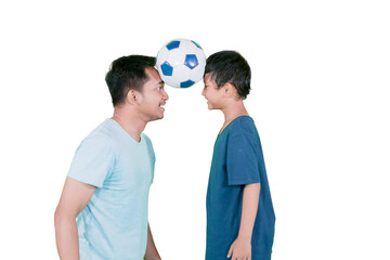Father and son balancing a soccer ball between their foreheads and smiling
