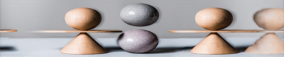 Three minimalist wooden figures carefully balance a polished stone, symbolizing mental balance and teamwork against a muted grey studio background.