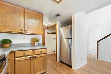 A kitchen with wood cabinets and a stainless steel fridge