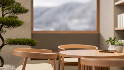 Book and pot plant on round wooden table with armchair aside bonsai tree and window with snowy mount