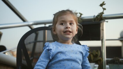 Smiling child sitting outdoors in casual clothing