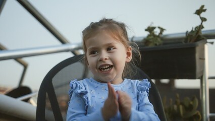 Happy child clapping hands outdoors in evening light