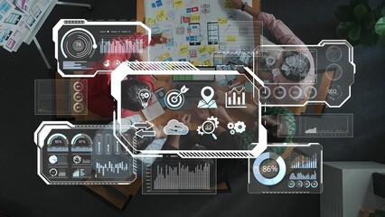 A top-down view of a collaborative workspace featuring digital data visualization tools, charts,...