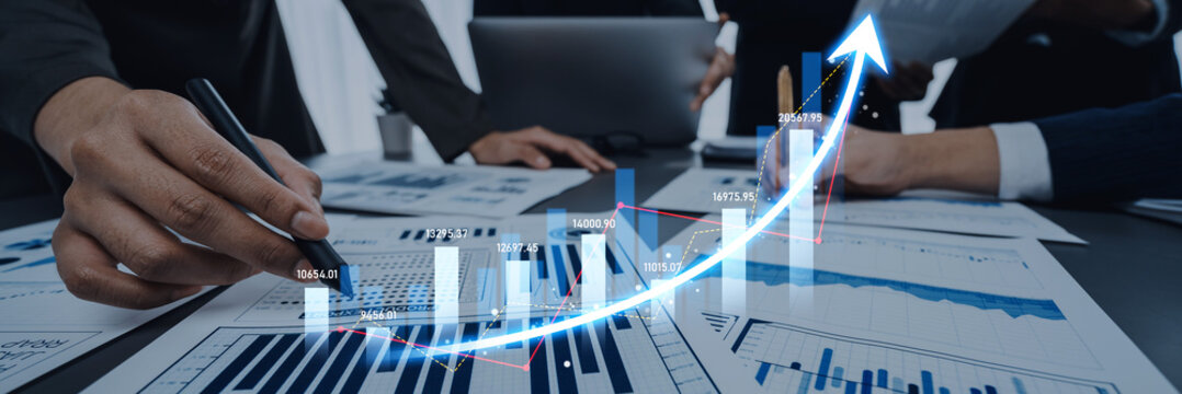 Business professionals work together at a desk, reviewing detailed financial reports and graphs, focusing on data analysis for effective growth strategies. Scalp