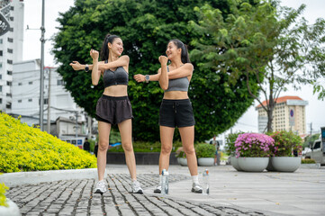 Asian woman friends in sportswear stretching warming up before exercise on pavement in a garden park