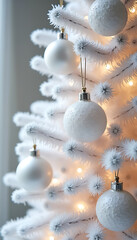 Close up of a flocked white tree adorned with textured white baubles and warm lights, evoking a serene winter feel