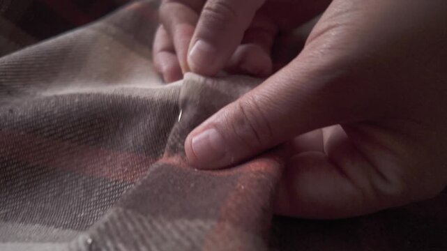 Close-up of a seamstress carefully pinning fabric to create a hem on a sewing machine. Detailed shot of hands working in a textile workshop, showcasing craftsmanship, precision, and the handmade garme