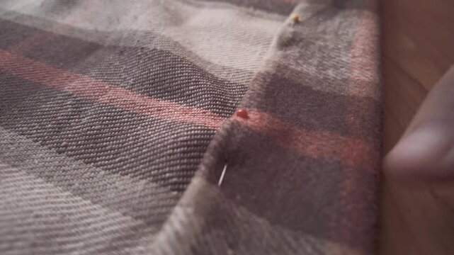 Close-up of a seamstress carefully pinning fabric to create a hem on a sewing machine. Detailed shot of hands working in a textile workshop, showcasing craftsmanship, precision, and the handmade garme