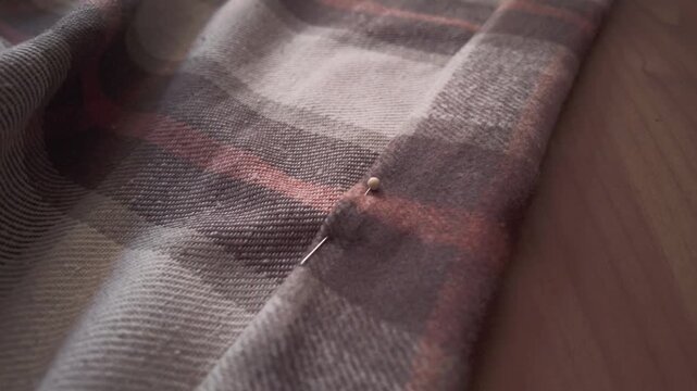 Close-up of a seamstress carefully pinning fabric to create a hem on a sewing machine. Detailed shot of hands working in a textile workshop, showcasing craftsmanship, precision, and the handmade garme