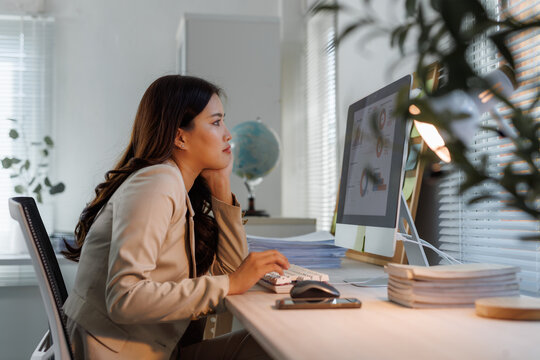 Asian businesswoman working late analyzing data on computer
