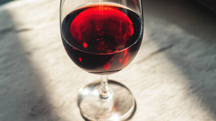 Naklejka premium A glass of rich red wine on a table, bathed in soft afternoon sunlight, invites relaxation Generative AI