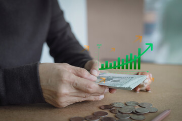 Hands counting US dollar bills with a growing bar chart overlay. Concept of financial growth, successful investment strategy, personal saving, future profit, and achieving money management goals.