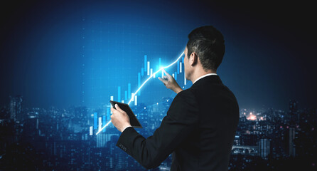 A businessman analyzes financial data trends through digital charts while overlooking a vibrant city skyline at night, showcasing a modern professional environment. Impute