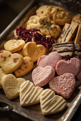 Heart shaped assorted cookies on metal tray with jam, powdered sugar and icing, cozy homemade dessert scene