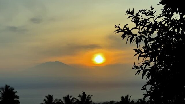 Serene Tropical Sunrise Over Misty Mountains With Silhouetted Foliage. Excellent footage for themes of nature, farming, and environmental clips.