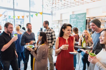 Group of diverse people socializing at a casual party. Men and women enjoying drinks and food,...