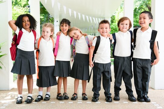 Group of diverse children in school uniforms with backpacks, smiling and standing together. Happy kids, school uniforms, backpacks, diverse group, smiling children. Cute little diverse school kids. - Powered by Adobe