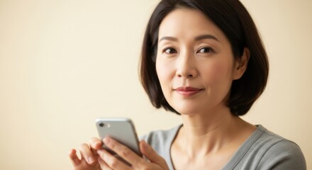Confident young woman smiling gently while using her smartphone in a neutral indoor setting