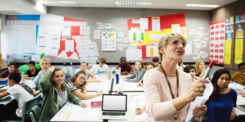 Classroom with diverse students and a teacher. Students engaged, teacher instructing. Bright, colorful classroom with educational materials on walls. Teacher teaching high school class.