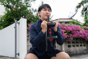 Young man exercising outdoors with dumbbell in hands, wearing sportswear and focused on fitness training in garden with flowers and greenery