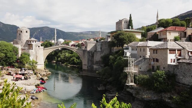 View of city and ancient arched stone bridge over Neretva river. Legacy of Ottoman architecture in Balkans 